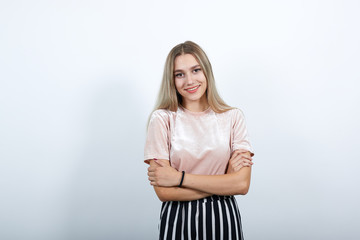 Fototapeta premium Side view of successful confident young woman in nice casual shirt hugging herself with opened eyes over isolated on white wall background in studio. People lifestyle concept.