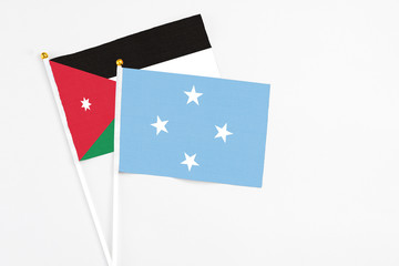 Micronesia and Jordan stick flags on white background. High quality fabric, miniature national flag. Peaceful global concept.White floor for copy space.