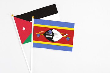 Swaziland and Jordan stick flags on white background. High quality fabric, miniature national flag. Peaceful global concept.White floor for copy space.