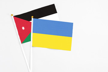 Ukraine and Jordan stick flags on white background. High quality fabric, miniature national flag. Peaceful global concept.White floor for copy space.