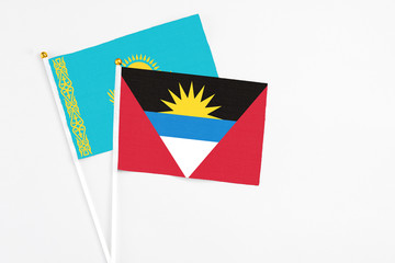 Antigua and Barbuda and Kazakhstan stick flags on white background. High quality fabric, miniature national flag. Peaceful global concept.White floor for copy space.