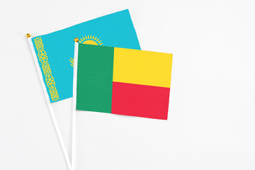 Benin and Kazakhstan stick flags on white background. High quality fabric, miniature national flag. Peaceful global concept.White floor for copy space.
