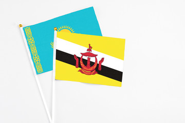 Brunei and Kazakhstan stick flags on white background. High quality fabric, miniature national flag. Peaceful global concept.White floor for copy space.