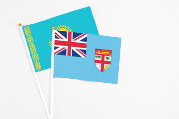 Fototapeta premium Fiji and Kazakhstan stick flags on white background. High quality fabric, miniature national flag. Peaceful global concept.White floor for copy space.