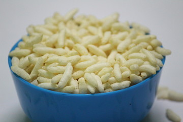 close up picture of Puffed rice on the blue bowl with white background