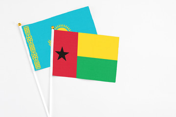 Guinea Bissau and Kazakhstan stick flags on white background. High quality fabric, miniature national flag. Peaceful global concept.White floor for copy space.