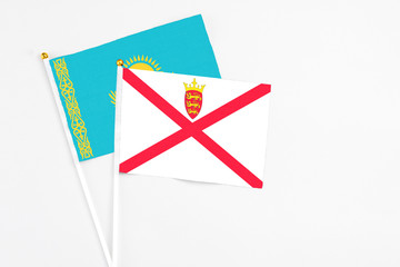 Jersey and Kazakhstan stick flags on white background. High quality fabric, miniature national flag. Peaceful global concept.White floor for copy space.