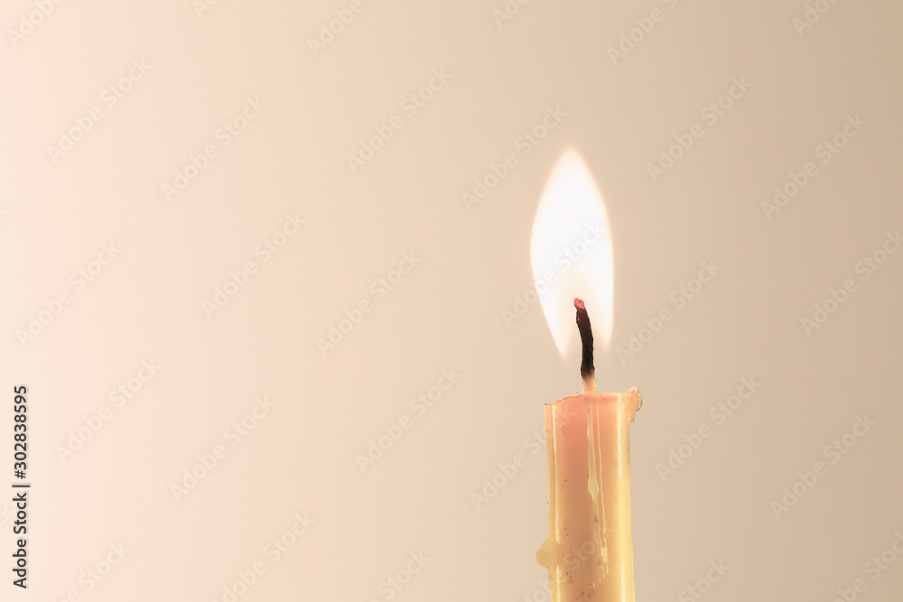 Wall mural burning yellow candle on warm background