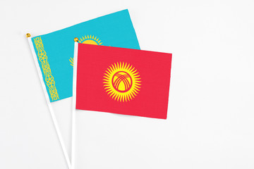 Kyrgyzstan and Kazakhstan stick flags on white background. High quality fabric, miniature national flag. Peaceful global concept.White floor for copy space.