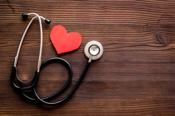 Health care concept. Heart icon and stethoscope on dark wooden background top view copy space