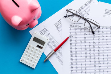 Taxes payment concept. Financial documents, piggy bank, calculator on blue background top view