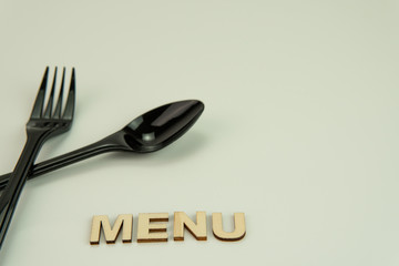 Selective focus of black shine spoon and fork with white background. Food or restaurant concept.