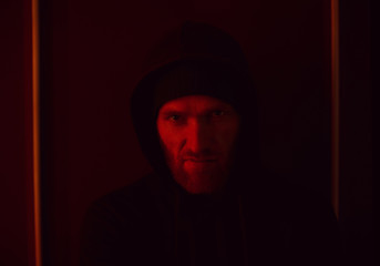 Portrait of angry young gangster wearing hoody making an angry face standing in dark