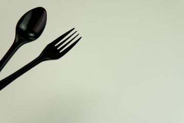Selective focus of black shine spoon and fork with white background. Food or restaurant concept.
