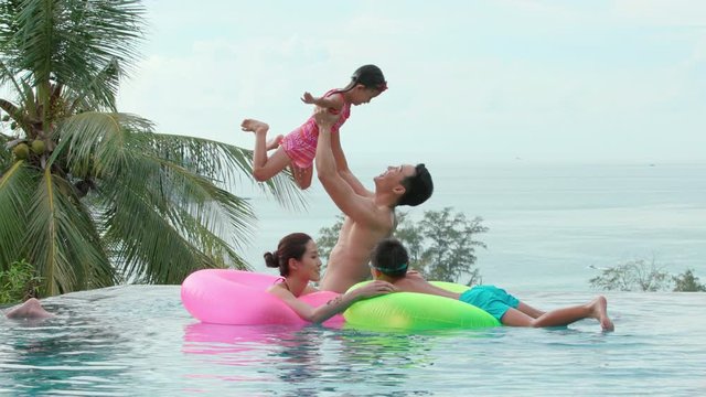 Happy young family having fun in swimming pool,4K
