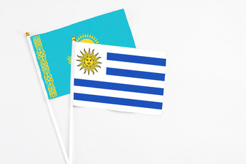 Uruguay and Kazakhstan stick flags on white background. High quality fabric, miniature national flag. Peaceful global concept.White floor for copy space.