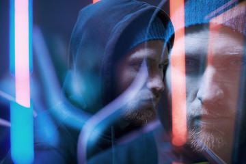 Blurred motion of young bearded man in black hoody shirt standing in dark room