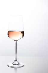 Rose wine in the glass at white background, romantic and elegant wine photo with copy space