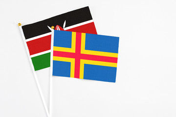 Aland Islands and Kenya stick flags on white background. High quality fabric, miniature national flag. Peaceful global concept.White floor for copy space.