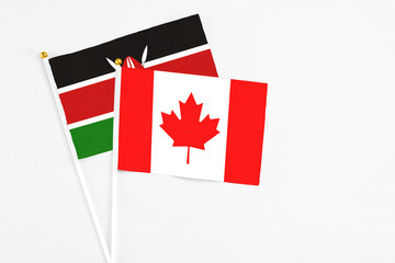 Canada and Kenya stick flags on white background. High quality fabric, miniature national flag. Peaceful global concept.White floor for copy space.