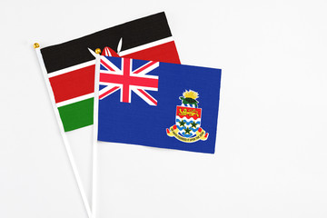 Fototapeta premium Cayman Islands and Kenya stick flags on white background. High quality fabric, miniature national flag. Peaceful global concept.White floor for copy space.