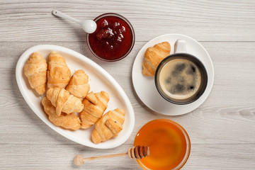 Cup of black coffee with saucer, fresh croissants on white porcelain dish