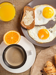 Fototapeta premium Plate with fried eggs, glass of orange juice and cup of black coffee