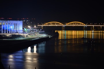 Night view of the Nizhny Novgorod stadium and the bridge across the Volga, reflected in the water