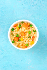 Ramen cup, instant noodles in a plastic cup, top-down shot on a blue background with a place for text