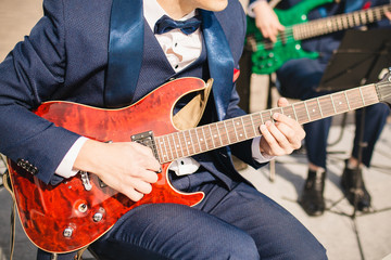 Guitarist virtuoso in an orchestra at a concert with a red electric guitar