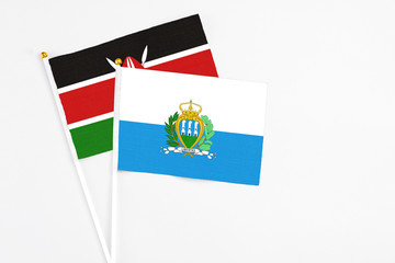 San Marino and Kenya stick flags on white background. High quality fabric, miniature national flag. Peaceful global concept.White floor for copy space.