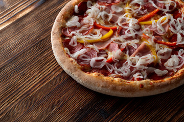 Hot italian meat pizza with sausage, ham and salami and bunch of sweet onion