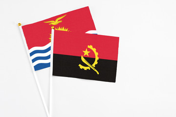 Angola and Kiribati stick flags on white background. High quality fabric, miniature national flag. Peaceful global concept.White floor for copy space.