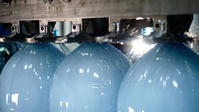 Manufacturing of pure fresh spring water on factory. Automatic conveyor line for bottling mineral water in plastic bottles on plant, closeup view. Production of artesian water from natural wells.