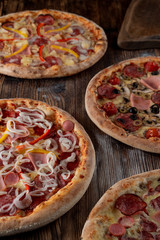 Different pizzas on wooden table in low light