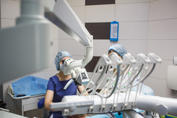 Female dentist looking into a microscope. Treatment of the patient through a microscope in the dental office