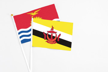 Brunei and Kiribati stick flags on white background. High quality fabric, miniature national flag. Peaceful global concept.White floor for copy space.