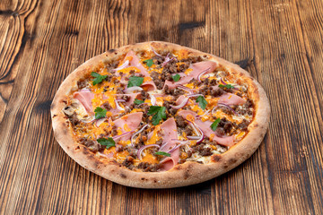 Pizza with minced meat and ham with cheese sauce on wooden table