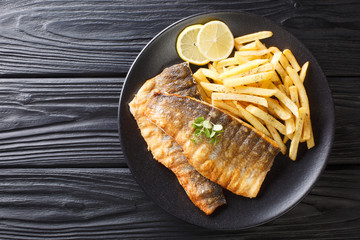 Spicy grilled sea bass fillet with crispy skin with french fries close-up on a plate. Horizontal...