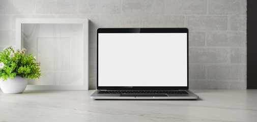 Minimal workspace with blank screen laptop computer and ceramic vase decorations