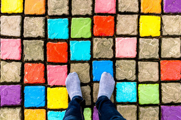 Foot wear socks and legs wear jeans seen from above on Multicolor and Colorful cement block...