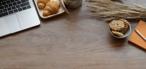 Comfortable workplace with laptop computer and breakfast on wooden table