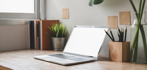 Cropped shot of comfortable workspace with blank screen laptop computer and office supplies