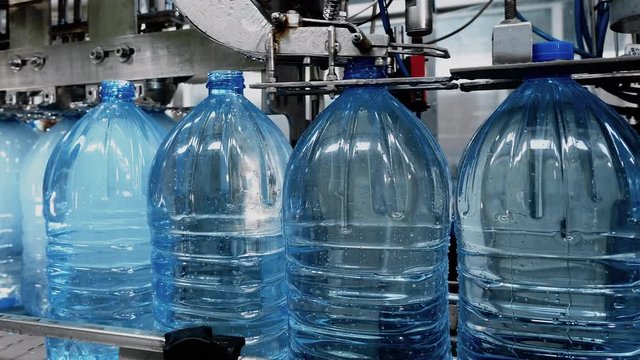 Automatic conveyor line for bottling mineral water and covering caps on plant. Industrial production artesian water from natural well in plastic bottles. Factory of manufacturing fresh spring water.