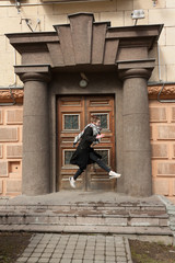 Fototapeta na wymiar cheerful happy girl in a coat and a scarf jumping of vintage doors