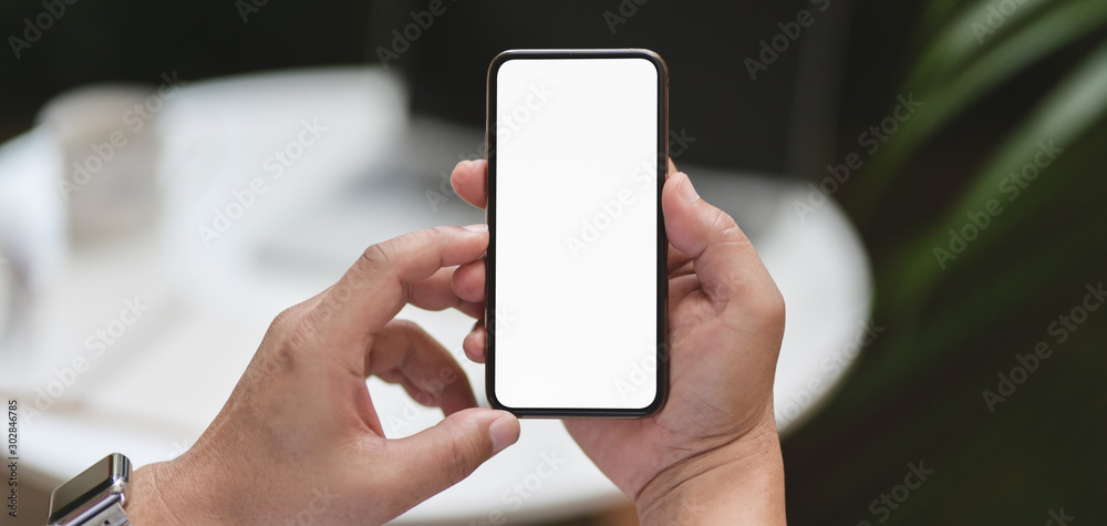 Wall mural cropped shot of man holding smartphone with outdoor workplace background