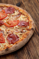 Closu up of salami pizza with melted cheese on wooden rustic table
