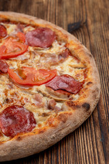 Closu up of salami pizza with melted cheese on wooden rustic table