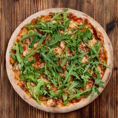 Prawn and cheese pizza with a bunch of fresh arugula