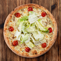 Chicken pizza with chicken breast, cherry tomatoes and fresh chinese cabbage on wooden table